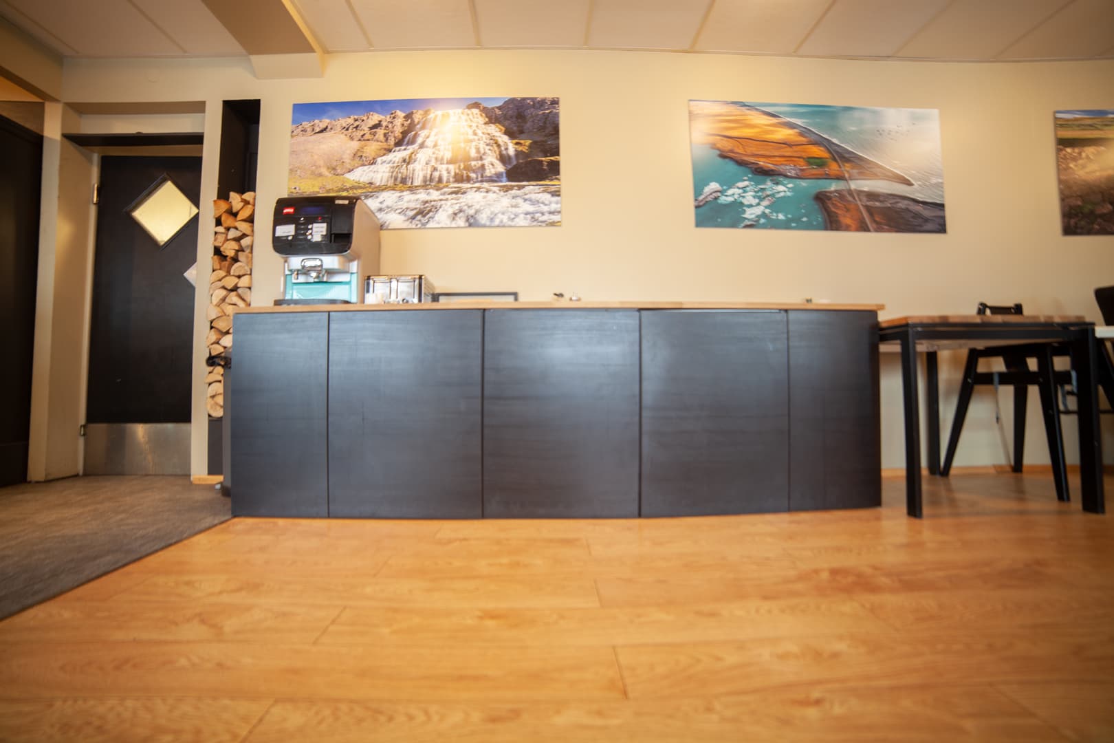 Dark counter with a coffee machine beside a stack of firewood