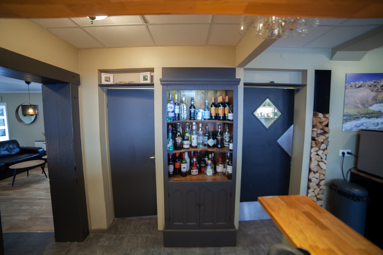 Cabinet of bottles beside a stack of firewood