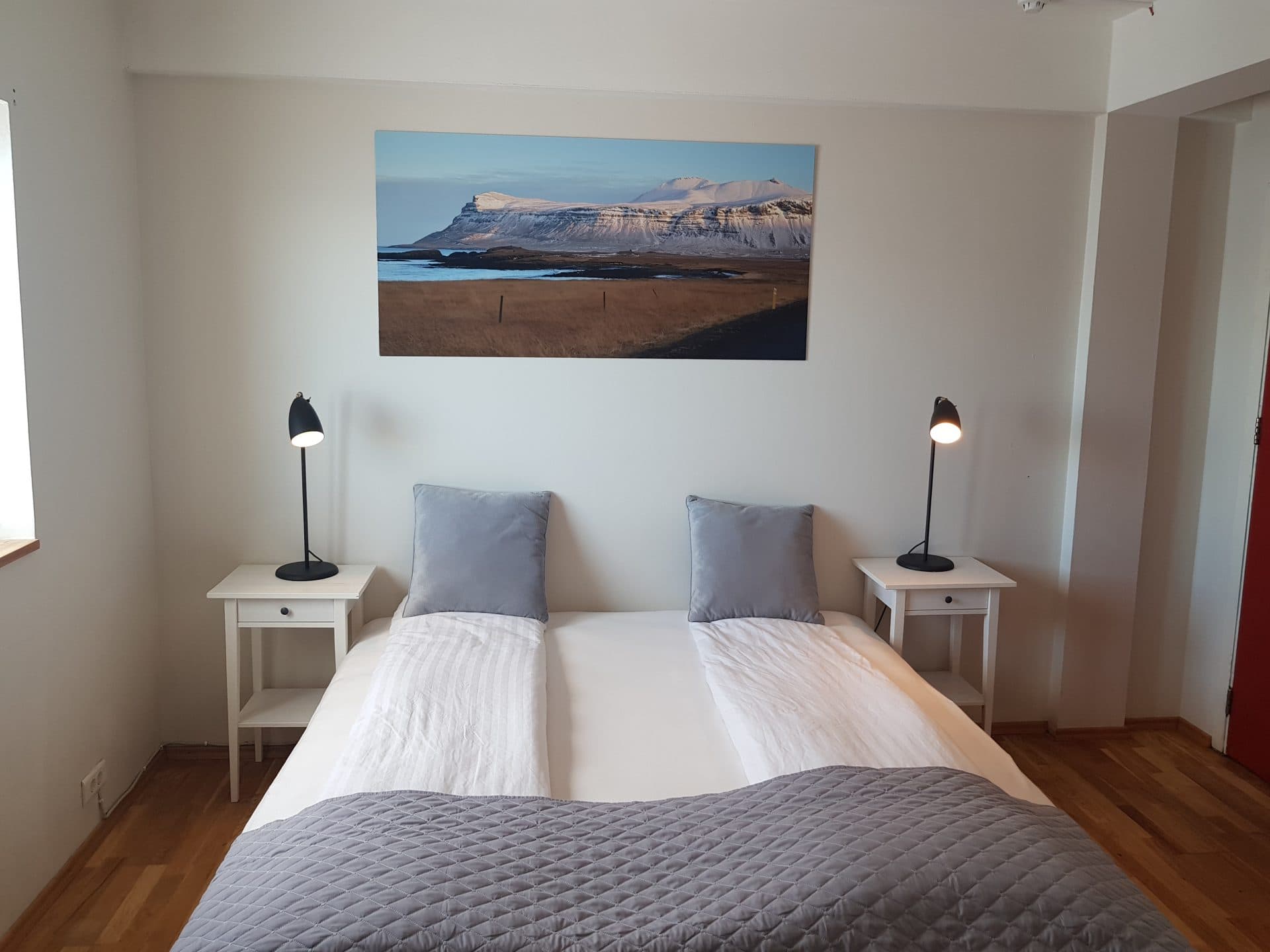 Bedroom with white bedding, bedside lamps and a mountain print
