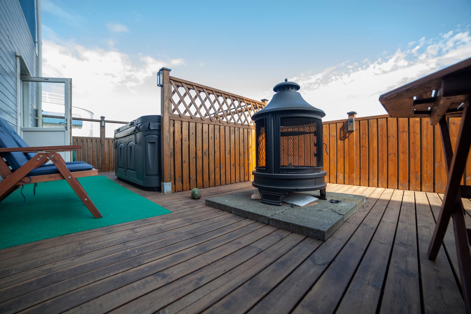 Wooden terrace with an outdoor fireplace and picnic benches