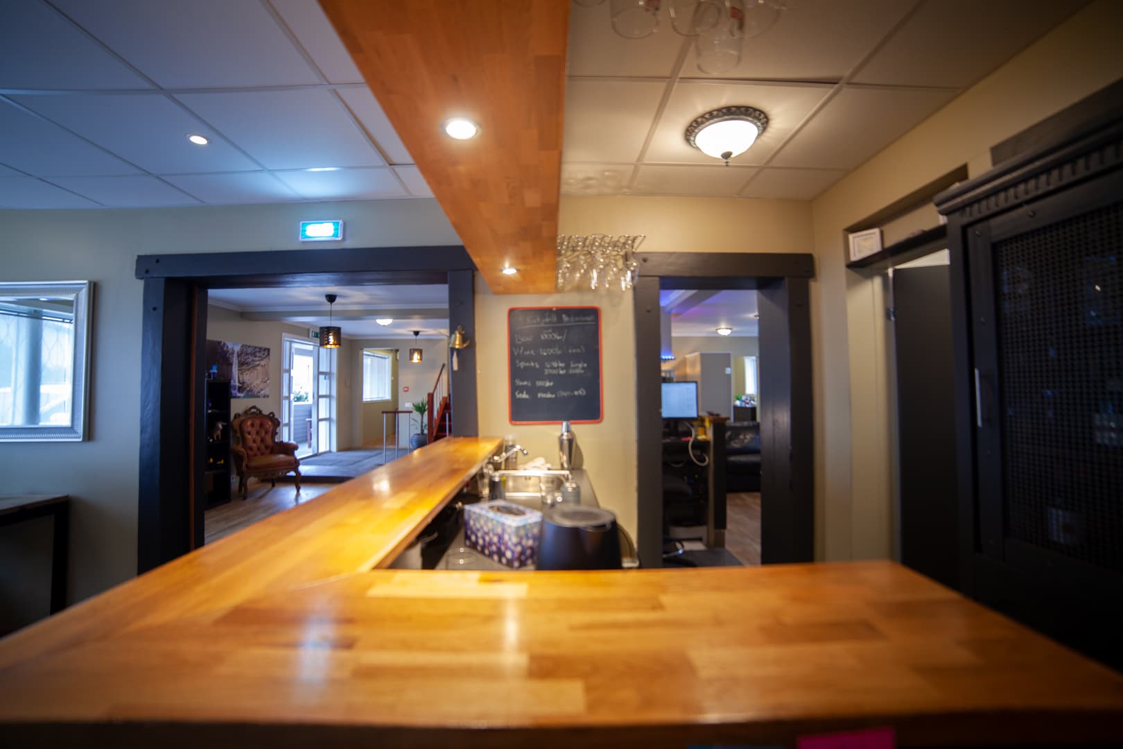 Long wooden counter with a chalkboard and hanging glasses